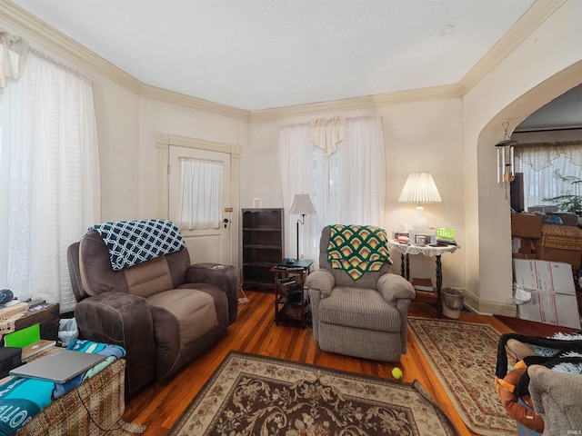 living room featuring wood-type flooring, a healthy amount of sunlight, and ornamental molding