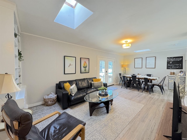 living room featuring crown molding, a skylight, french doors, and light wood-type flooring