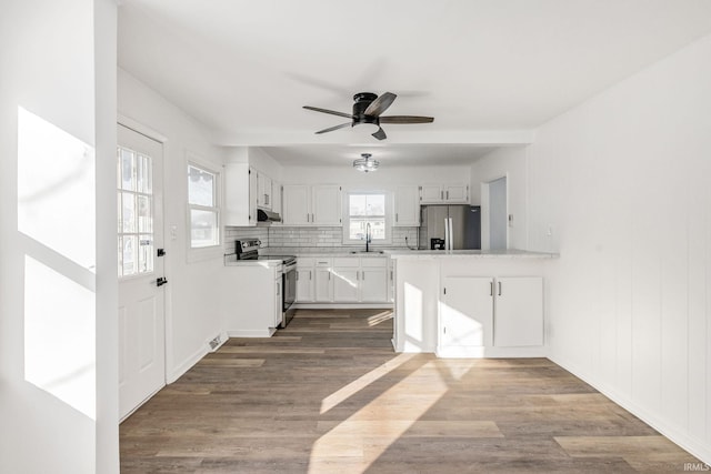 kitchen with appliances with stainless steel finishes, white cabinetry, sink, backsplash, and kitchen peninsula