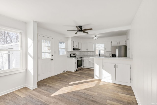 kitchen with plenty of natural light, stainless steel appliances, light hardwood / wood-style floors, and white cabinets