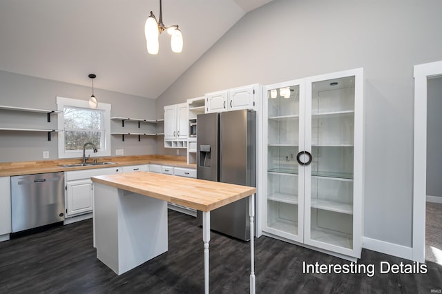 kitchen with appliances with stainless steel finishes, decorative light fixtures, butcher block counters, and white cabinets