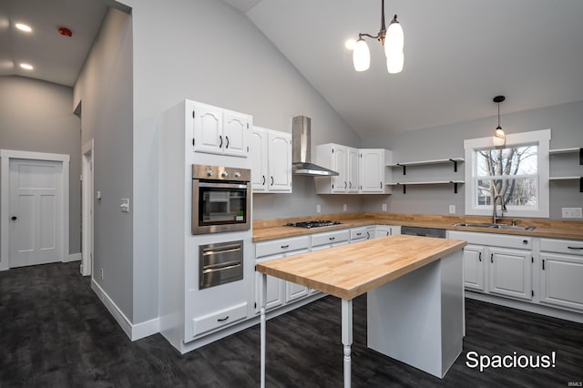 kitchen featuring wall chimney exhaust hood, hanging light fixtures, and white cabinets