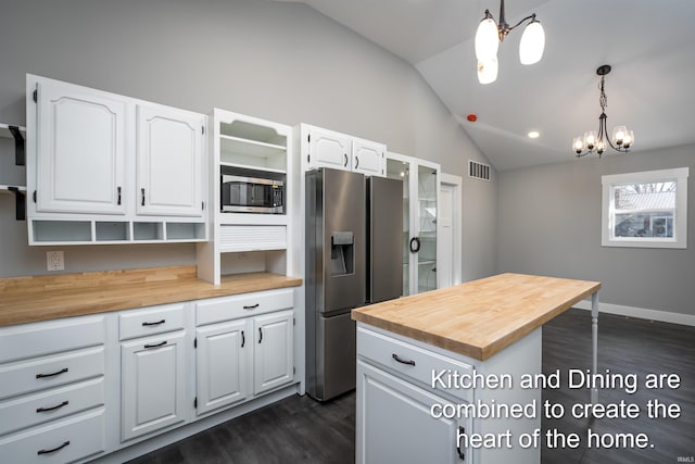 kitchen with lofted ceiling, appliances with stainless steel finishes, butcher block counters, hanging light fixtures, and white cabinets