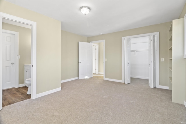 unfurnished bedroom with light carpet and connected bathroom