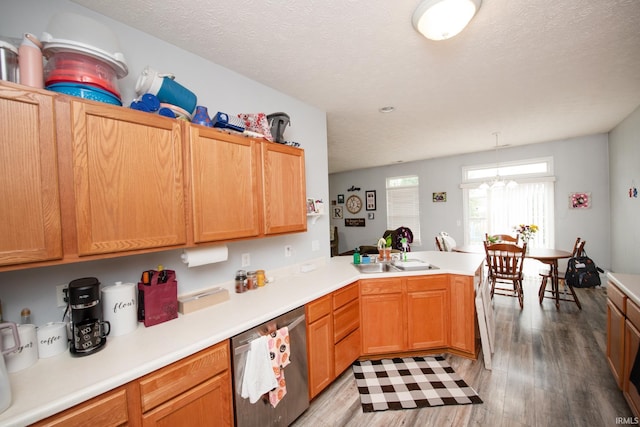 kitchen with sink, light wood-type flooring, dishwasher, kitchen peninsula, and pendant lighting