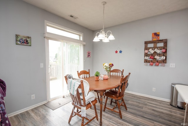 dining space with hardwood / wood-style flooring and a chandelier