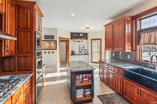 kitchen with appliances with stainless steel finishes, tasteful backsplash, sink, a center island, and light tile patterned floors