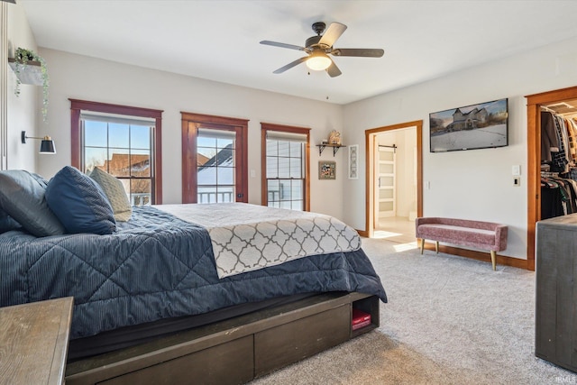 bedroom featuring ceiling fan, carpet flooring, ensuite bath, and a spacious closet