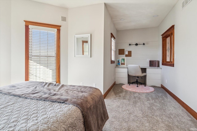 bedroom featuring multiple windows, built in desk, and light carpet