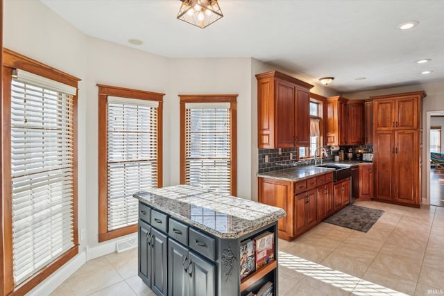 kitchen with gray cabinets, a kitchen island, tasteful backsplash, sink, and light tile patterned floors