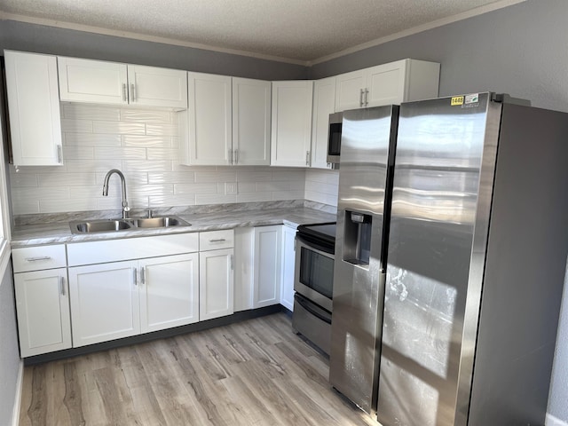 kitchen with appliances with stainless steel finishes, white cabinetry, sink, a textured ceiling, and light hardwood / wood-style flooring