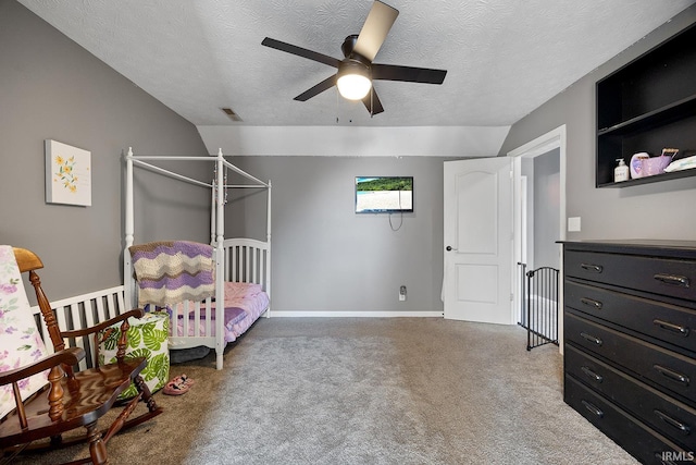 bedroom with lofted ceiling, a textured ceiling, ceiling fan, and carpet