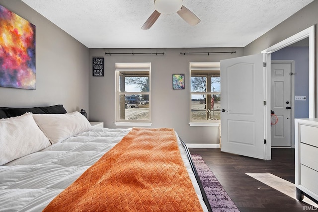 bedroom with a textured ceiling, dark wood-type flooring, and ceiling fan