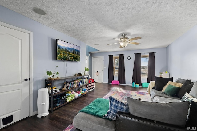 living room featuring ceiling fan, dark wood-type flooring, and a textured ceiling