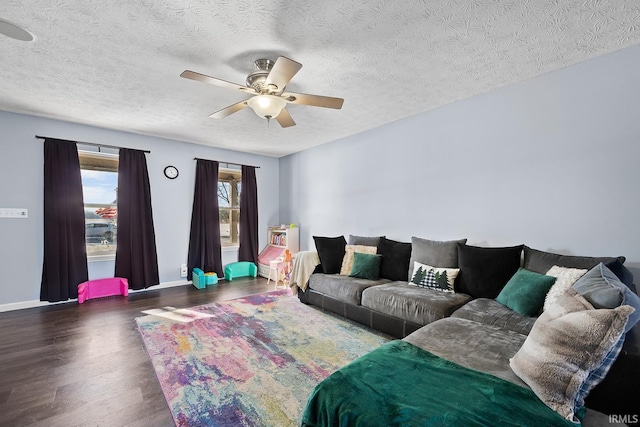 living room with dark wood-type flooring, ceiling fan, and a textured ceiling