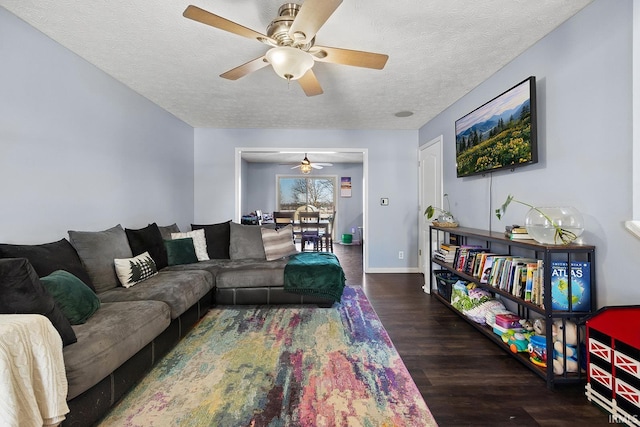 living room featuring dark wood-type flooring, ceiling fan, and a textured ceiling