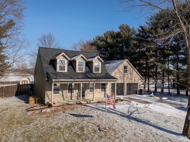 cape cod-style house featuring a garage and a porch