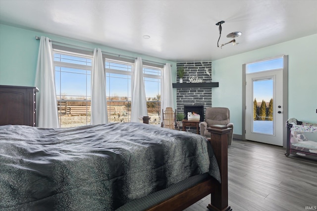 bedroom featuring multiple windows, hardwood / wood-style floors, access to exterior, and a fireplace