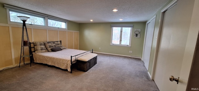 carpeted bedroom with multiple windows, a textured ceiling, and baseboard heating