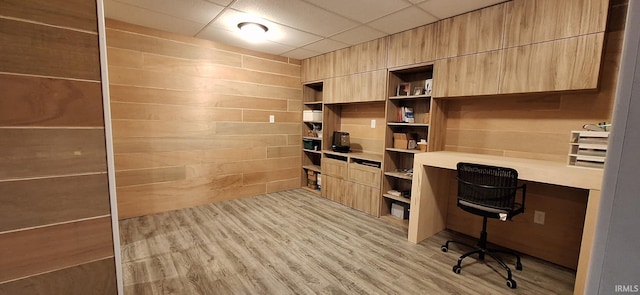 office with built in desk, a drop ceiling, and light hardwood / wood-style floors