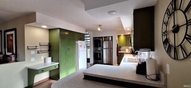 kitchen with hardwood / wood-style floors, stainless steel refrigerator, sink, white fridge, and a textured ceiling