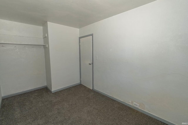 unfurnished bedroom featuring dark carpet and a closet