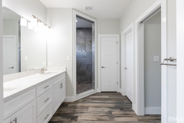 bathroom featuring hardwood / wood-style flooring, vanity, and a tile shower