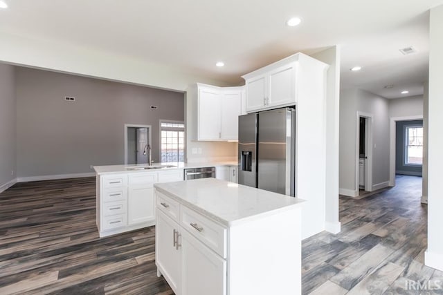 kitchen featuring sink, appliances with stainless steel finishes, white cabinetry, a center island, and kitchen peninsula