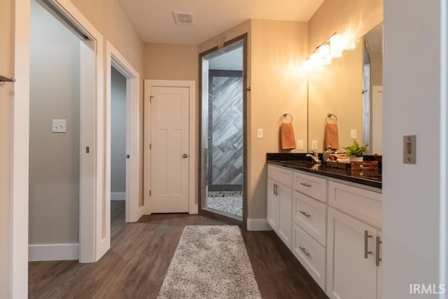 bathroom with hardwood / wood-style flooring, vanity, and walk in shower