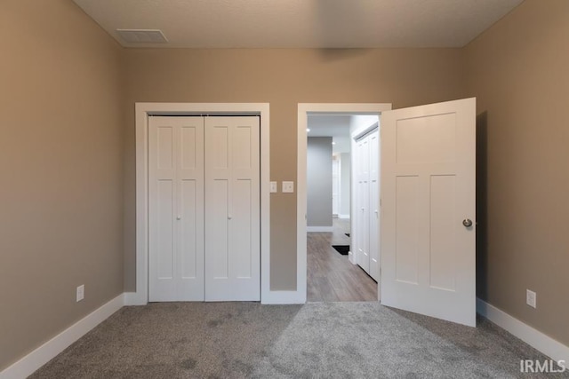 unfurnished bedroom with light colored carpet and a closet