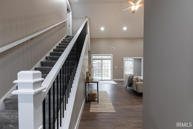 stairs featuring wood-type flooring, a towering ceiling, and ceiling fan