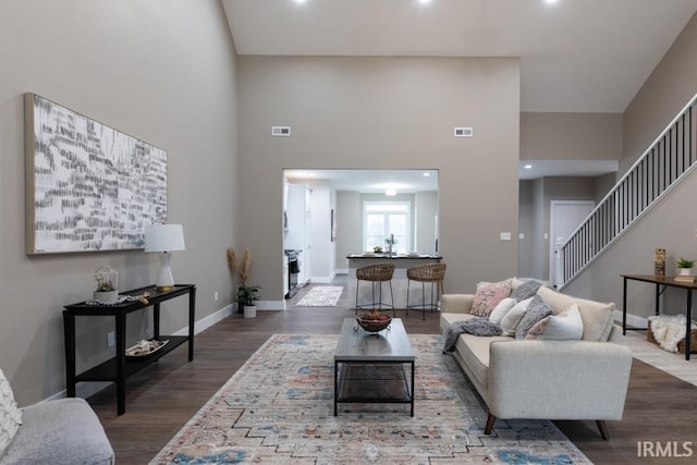 living room with a towering ceiling and dark hardwood / wood-style flooring