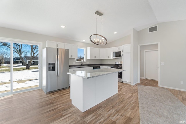 kitchen featuring pendant lighting, sink, stainless steel appliances, white cabinets, and vaulted ceiling