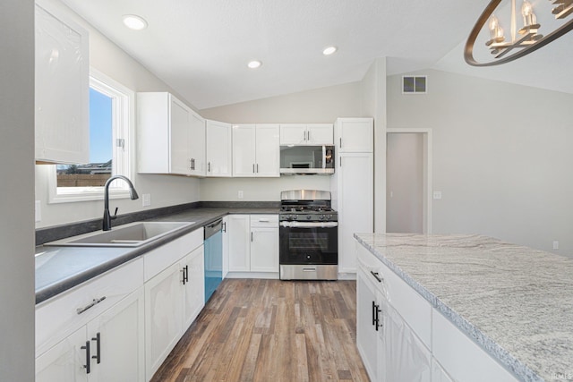 kitchen featuring white cabinetry, appliances with stainless steel finishes, pendant lighting, and lofted ceiling