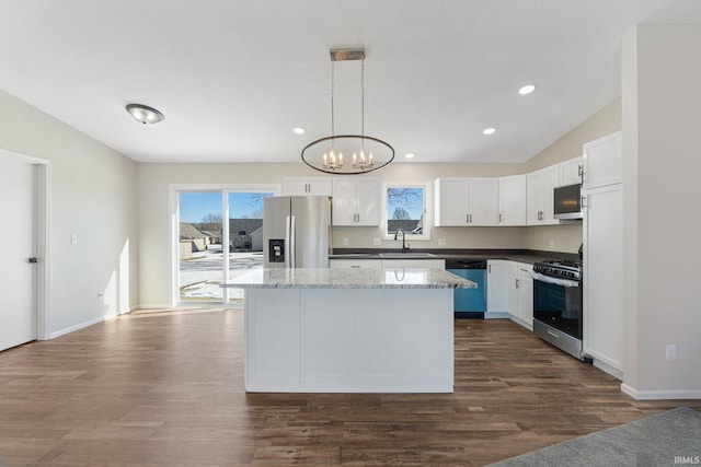 kitchen with a kitchen island, appliances with stainless steel finishes, pendant lighting, white cabinets, and dark hardwood / wood-style flooring