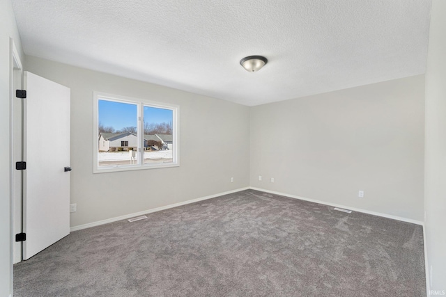 spare room featuring a textured ceiling and dark colored carpet