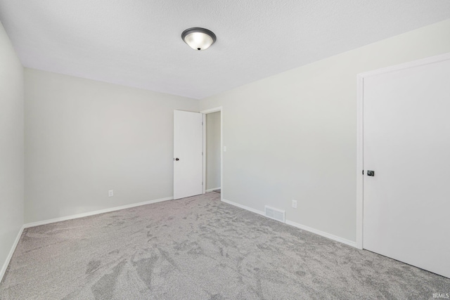 spare room with a textured ceiling and carpet flooring