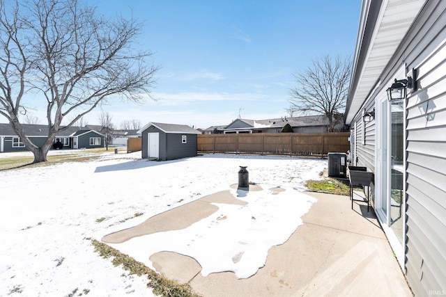 yard layered in snow featuring central AC unit and a shed