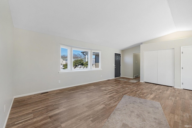 unfurnished bedroom featuring vaulted ceiling and hardwood / wood-style floors