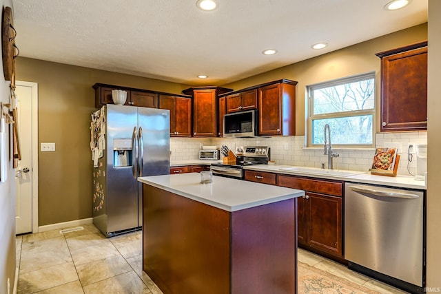 kitchen featuring appliances with stainless steel finishes, tasteful backsplash, sink, a center island, and light tile patterned floors