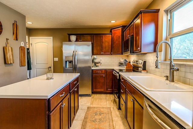 kitchen featuring sink, decorative backsplash, a center island, light tile patterned floors, and stainless steel appliances