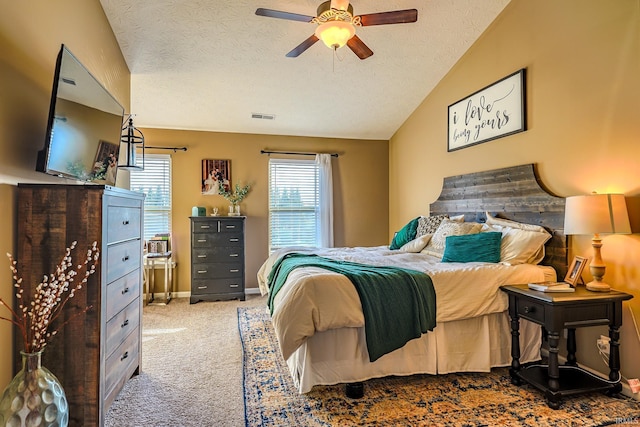 bedroom with lofted ceiling, light carpet, a textured ceiling, and ceiling fan