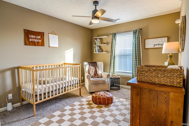 bedroom with ceiling fan, a textured ceiling, carpet, and a crib