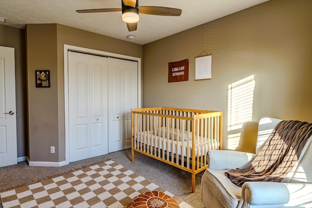 carpeted bedroom featuring ceiling fan, a closet, and a nursery area