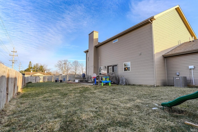 back of property with cooling unit, a yard, and a playground