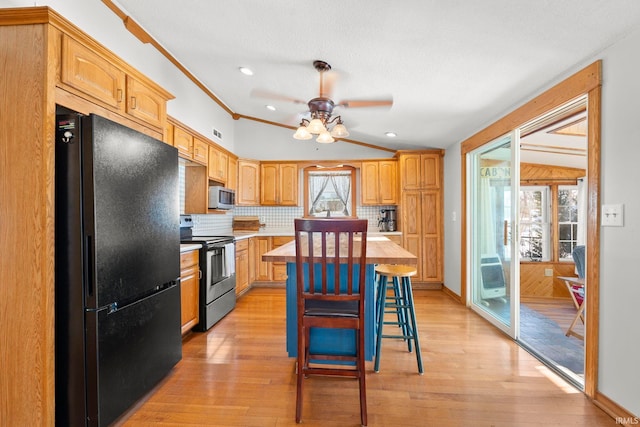 kitchen featuring crown molding, stainless steel appliances, light hardwood / wood-style floors, a kitchen island, and decorative backsplash