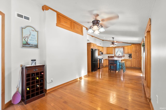 kitchen with a breakfast bar, tasteful backsplash, light hardwood / wood-style flooring, appliances with stainless steel finishes, and a kitchen island