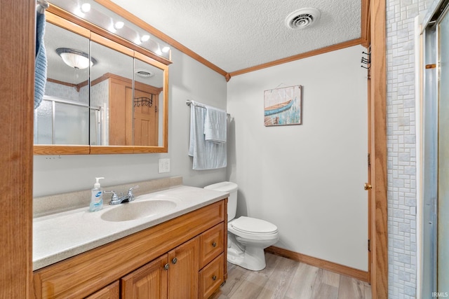 bathroom with hardwood / wood-style floors, an enclosed shower, vanity, ornamental molding, and a textured ceiling