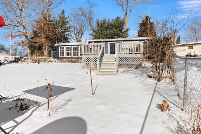 snow covered back of property with a deck