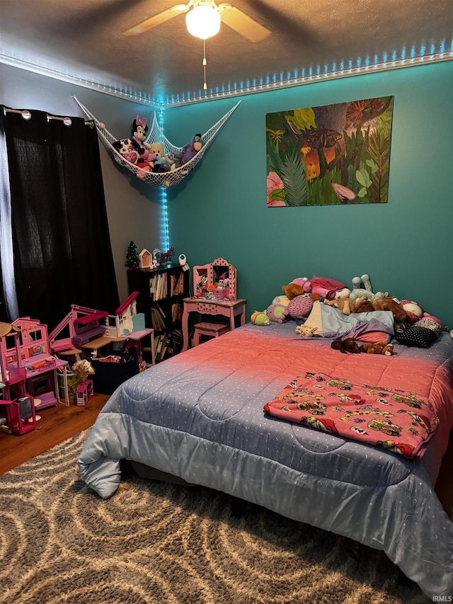 bedroom featuring hardwood / wood-style floors, a textured ceiling, and ceiling fan